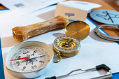 Close-up of old compass, paper lying on table. Equipment for tourism, navigation