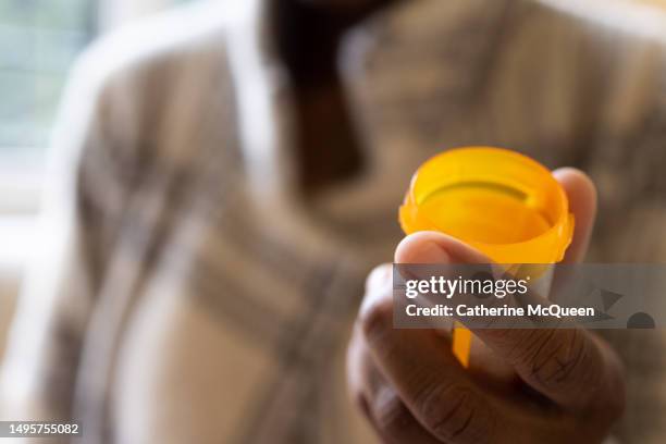 black woman holding open prescription pill bottle - verschreibungspflichtiges medikament stock-fotos und bilder