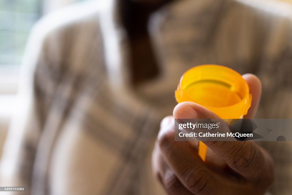 Black woman holding open prescription pill bottle