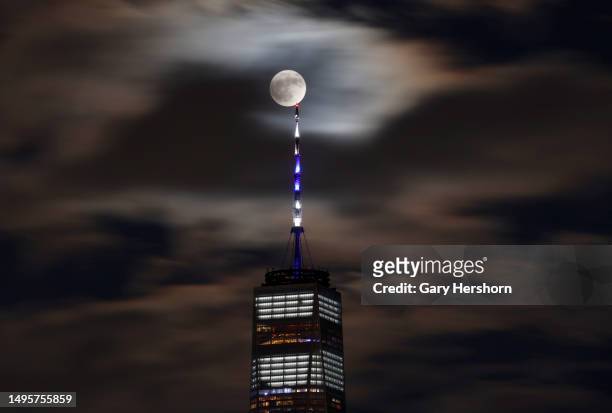 Rapidly moving clouds float past the full Strawberry Moon as it rises behind One World Trade Center in New York City on June 3 as seen from Jersey...