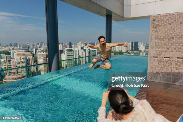 asian couple on holiday taking pictures by the poolside - the weekend in news around the world stockfoto's en -beelden