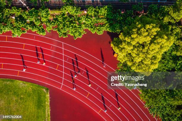 aerial view of runners running on red tartan track in the morning, like music note - jogging track stock pictures, royalty-free photos & images