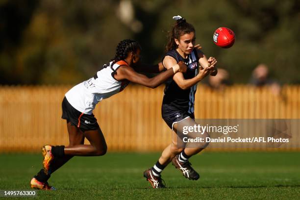 Caitlin Charles of the Falcons handballs whilst being tackled by Marika Carlton of Northern Territory during the round nine Coates Talent League...