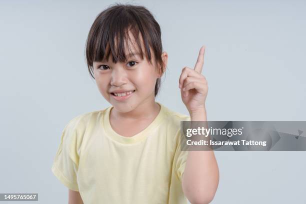 happy child girl pointing up with an idea, isolated on a white background. this cute and adorable portrait captures the curiosity and imagination of childhood. - point stock pictures, royalty-free photos & images