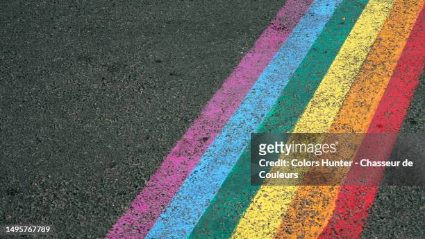 the rainbow flag of the lgbt+ community painted and patinated on the asphalt of a street in paris, france - castro district stock pictures, royalty-free photos & images