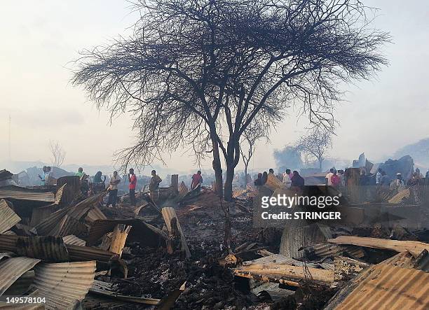 This photo taken on July 30 shows residents of the sprawling Dadaab refugee camp in Kenya looking among the debris of their homes after an accidental...