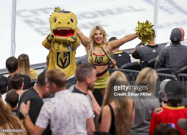 The Vegas Golden Knights mascot Chance the Golden Gila Monster and a member of the Vegas Golden Knights Vegas Vivas cheerleaders hype up the crowd in...