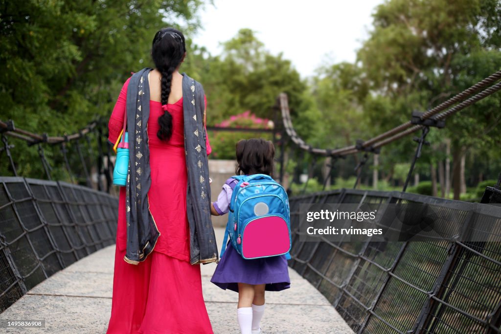 Rear view of schoolgirl going to school with her mother