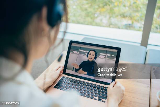 the asian businesswoman is using a laptop and a headset microphone for video calls, participating in remote meetings to discuss matters with colleagues or work partners. - matters stock pictures, royalty-free photos & images