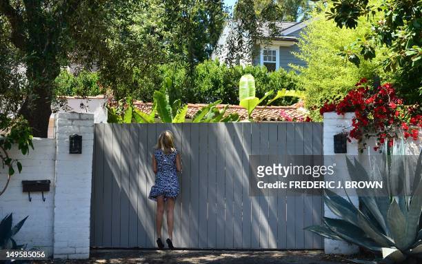 Woman jumps for a better view through the gate outside the house where Marilyn Monroe died in Brentwood, on July 28, 2012 in California, during a...