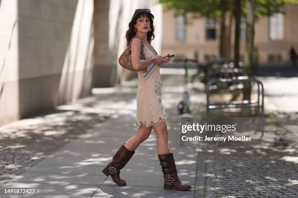 Lea Naumann wearing Miu Miu brown leather Metall boots, Prada beige leather Moon bag, Nisse mini dress with crystal and Pearl details, Acne Studios...