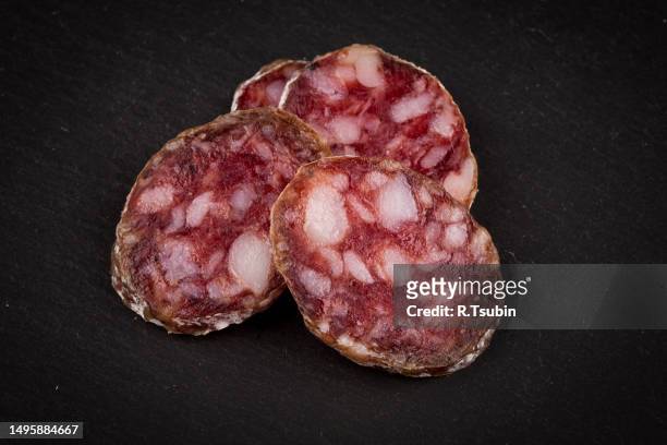 slices of salami on a dark stone board as a background - pepperoni slice stock pictures, royalty-free photos & images