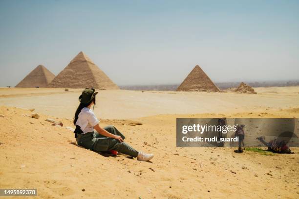 egypte, le caire, touriste asiatique assise sur des rochers avec la grande pyramide de gizeh en arrière-plan - cairo photos et images de collection