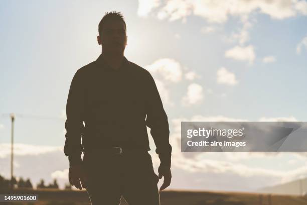 front view of man standing with his eyes closed dressed in black on a sunny day.. - mid adult men stock pictures, royalty-free photos & images