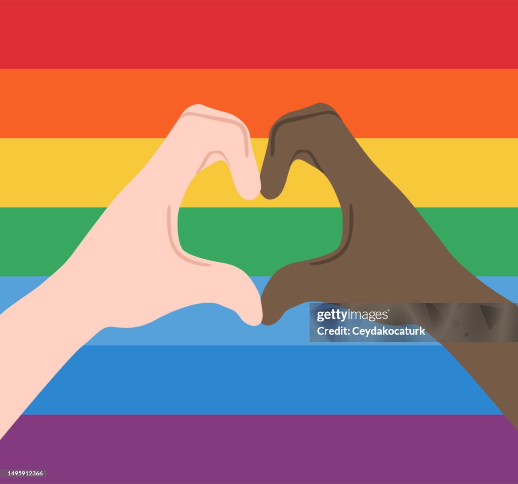Heart shape hands with rainbow flag background. LGBTQIA pride concept.