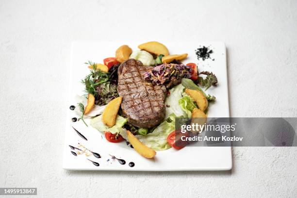 grilled t-bone steak with vegetable garnish. dish on white square plate. lunch. fried pork with salad. photo for menu. white background. view from above. copy space - t bone steak stock pictures, royalty-free photos & images
