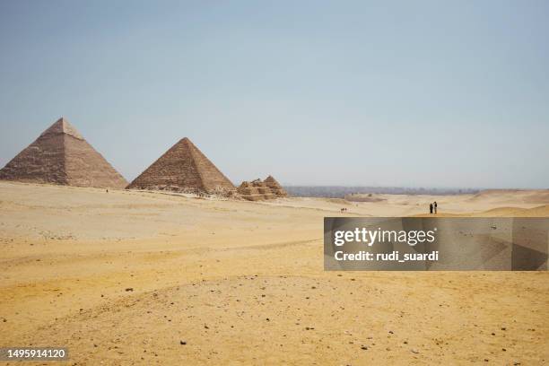 asiatisches paar, das auf wüste auf dem hintergrund der pyramiden von gizeh steht - archäologe stock-fotos und bilder