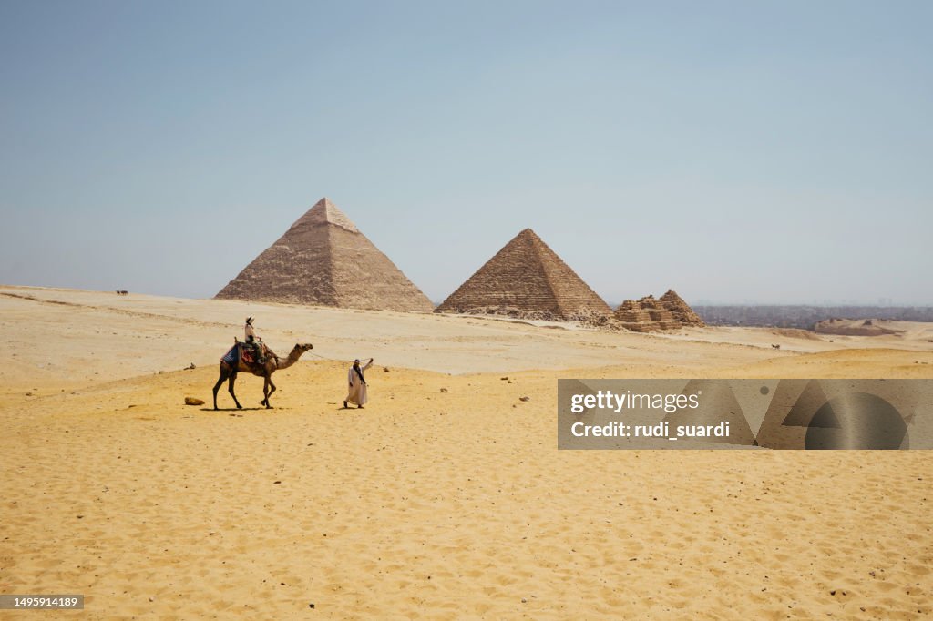 Bedouin leading a camel with tourist in the desert