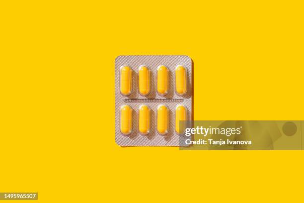 blister with pills and capsules on yellow background. - yellow capsules stock pictures, royalty-free photos & images