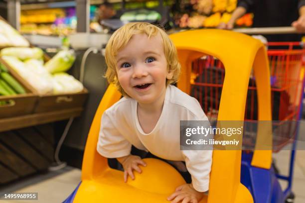 small blonde child boy in toy car. - shopping cart toys stock pictures, royalty-free photos & images