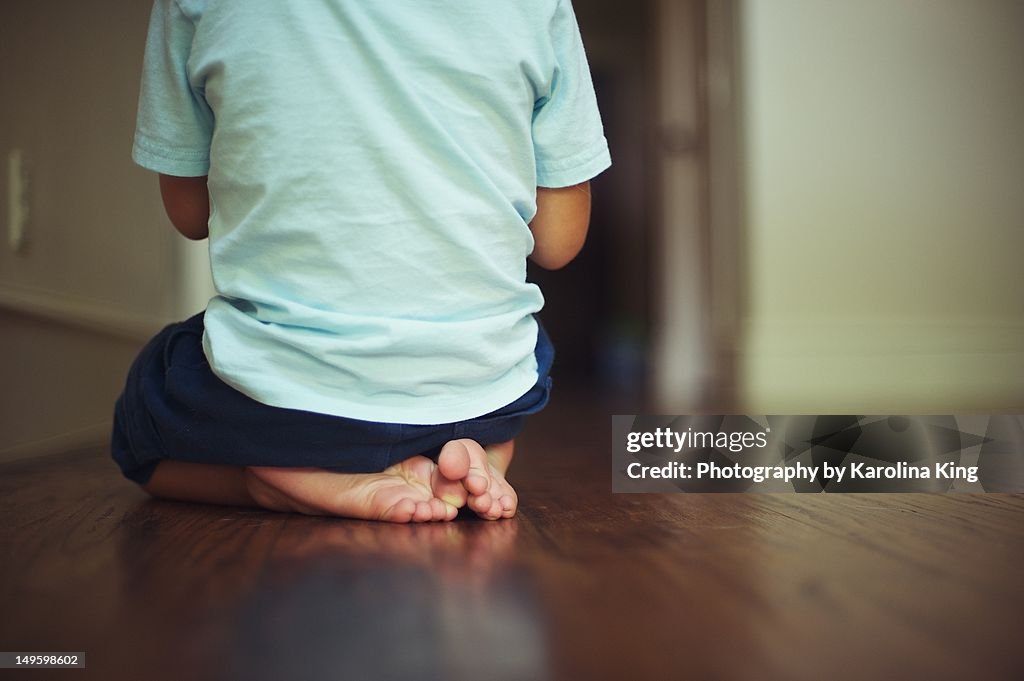 Small boy with back to camera with visible feet