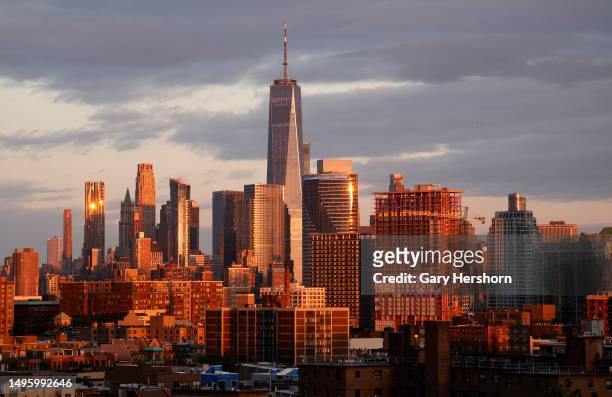 The sun sets on the skyline of lower Manhattan and One World Trade Center in New York City and buildings in the Newport neighborhood of Jersey City,...