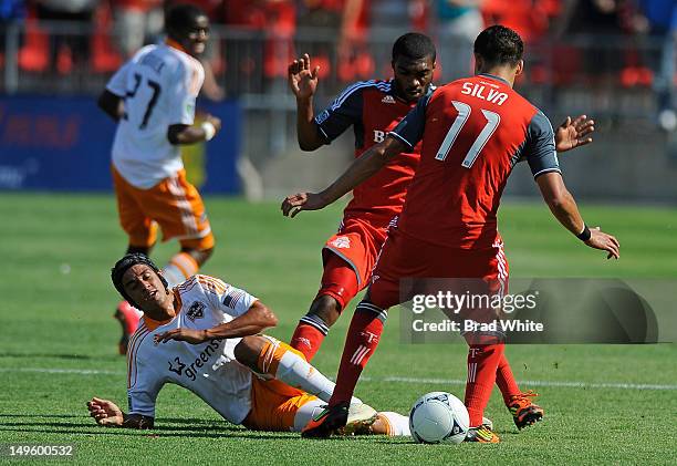 Ashtone Morgan and Luis Silva of the Toronto FC battle for the ball with Calen Carr of the Houston Dynamo during MLS game action July 28, 2012 at BMO...