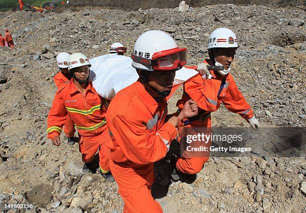 Rescuers carry a victim's body after a mudslide occurred at an iron ore mine on July 31, 2012 in Xinyuan, China. At least 16 people were killed and...