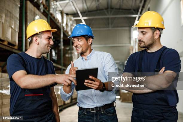 glücklicher inspektor mit digitalem tablet mit lagerarbeitern in einem lagerraum. - ok werk stock-fotos und bilder