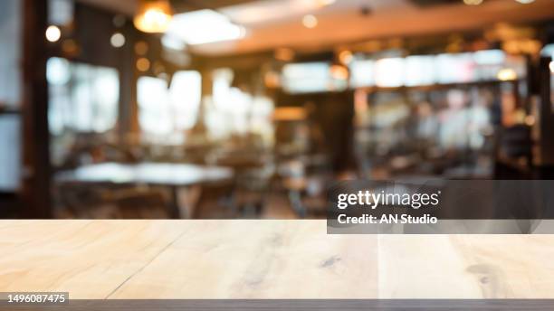 wooden board empty table in front of blurred background. brown wood over blur in coffee shop. can be used for display or montage your products. mock up for display of product. - coffe shop stock-fotos und bilder