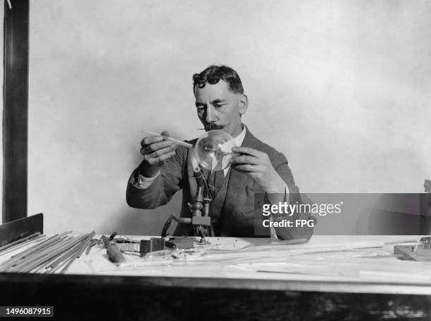 Man with a waxed moustache conducts a glass-blowing demonstration at an industrial exhibition, held at Selfridges department store in the West End of...