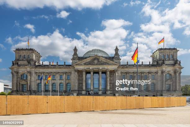 deutscher bundestag behind a construction site fence - reichstag building with german flags (german parliament building) - berlin, germany - central berlin stock-fotos und bilder