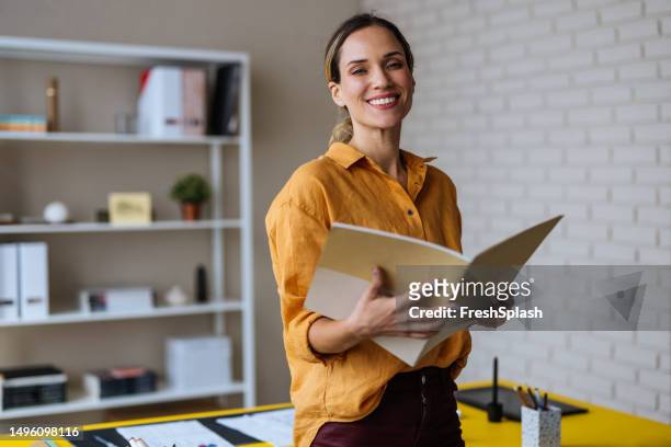 una bella donna d'affari bionda felice che guarda la macchina fotografica mentre tiene un taccuino - teacher desk foto e immagini stock