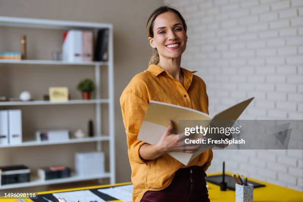 a happy beautiful blonde businesswoman looking at camera while holding a notebook - school teacher success bildbanksfoton och bilder