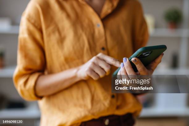 an unrecognizable businesswoman using her mobile phone while working in the office - mobile phone in hand stock pictures, royalty-free photos & images