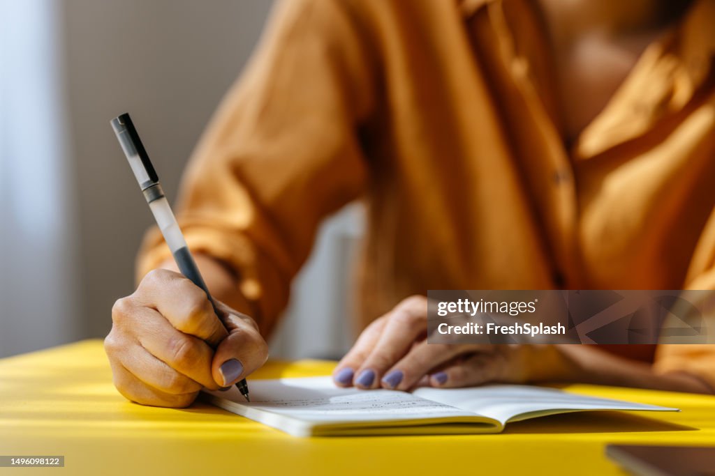 Uma empresária irreconhecível fazendo algumas anotações em seu caderno enquanto trabalha no escritório