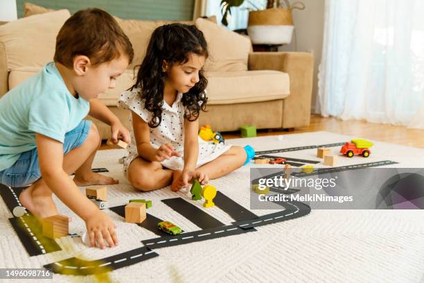 children crawling on the carpet and playing traffic with toys, learning about traffic rules - kruipen stockfoto's en -beelden