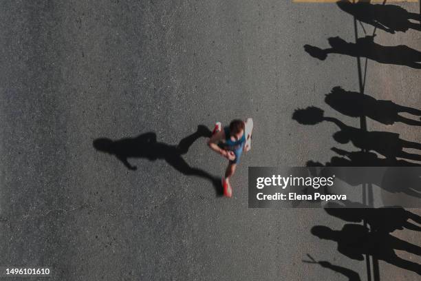 unknown male triathlete running fast marathon distance and greeting fans, high angle view, abstract sports background - marathon feet stock pictures, royalty-free photos & images