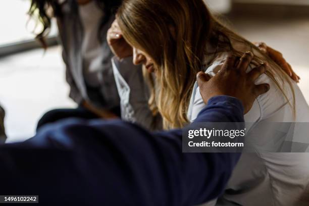 mature woman sitting with head in hand while sharing her emotions during a group therapy session - emotional support stock pictures, royalty-free photos & images