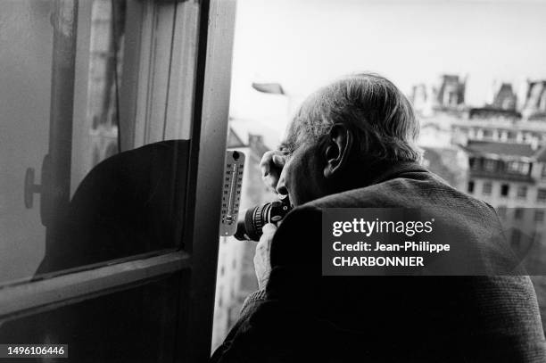 Le photographe hongrois André Kertész à la fenêtre d'un appartement à Paris, circa 1970, France.