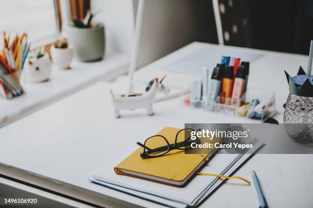 yellow notepad  with eraser, eyeglasses and pen resting in white table - notepad table stockfoto's en -beelden