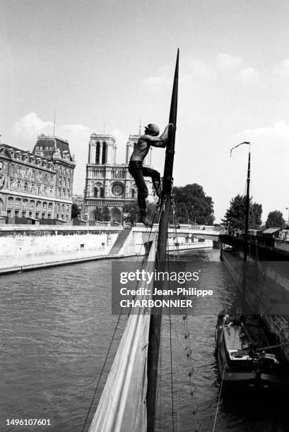 Marin escaladant le mât d'un bateau à voile sur la Seine à Paris, circa 1960.