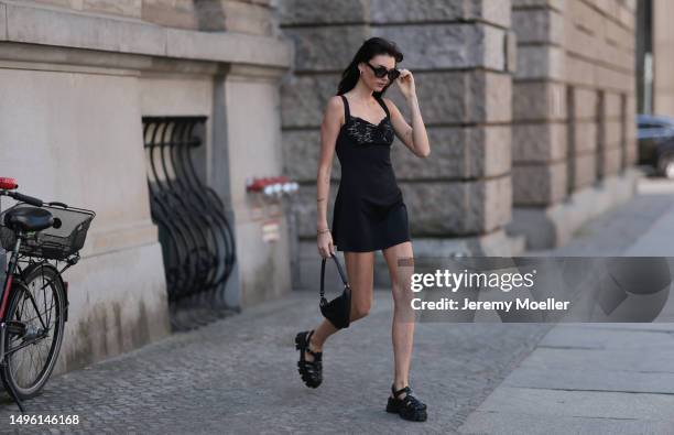 Celine Bethmann wears Celine black shades, Prada triangle black leather bag, Prada black rubber sandals, House of CB black mini dress on June 05,...