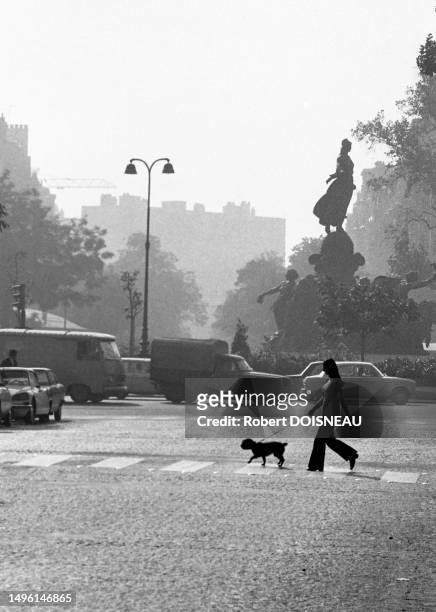 Silhouette d'une jeune femme avec son chien traversant l'avenue Philippe Auguste vers Nation en septembre 1972 à Paris.