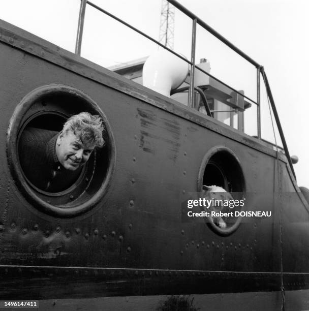 Marinier et son chien sortant la tête chacun d'un hublot d'une péniche a? Conflans Sainte-Honorine en mars 1958.