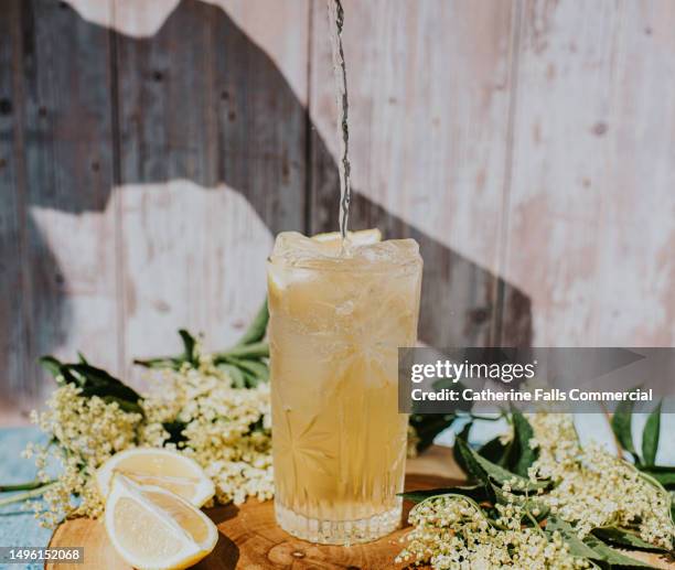 a fresh cold lemon lemon drink on a wooden chopping board - citroen frisdrank stockfoto's en -beelden