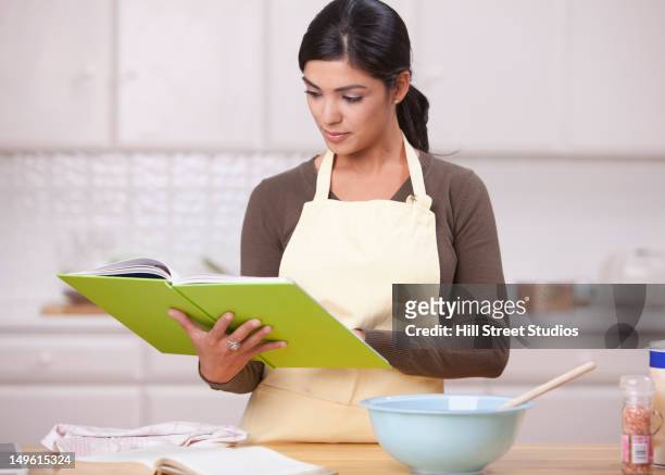 hispanic woman reading recipe in kitchen - baking reading recipe stockfoto's en -beelden