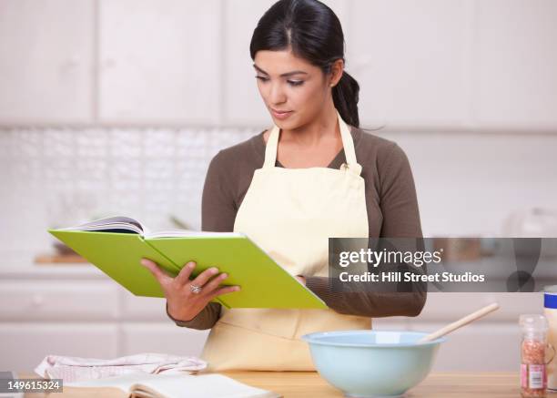 hispanic woman reading recipe in kitchen - reading cookbook stock pictures, royalty-free photos & images