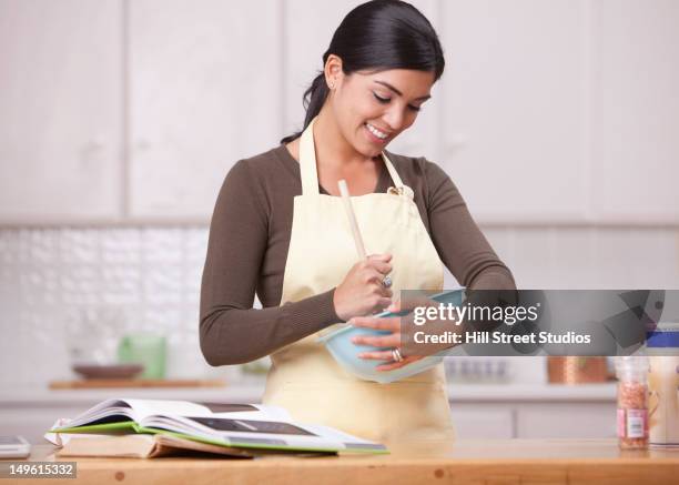 hispanic woman mixing batter in bowl in kitchen - mixing bowl stock pictures, royalty-free photos & images