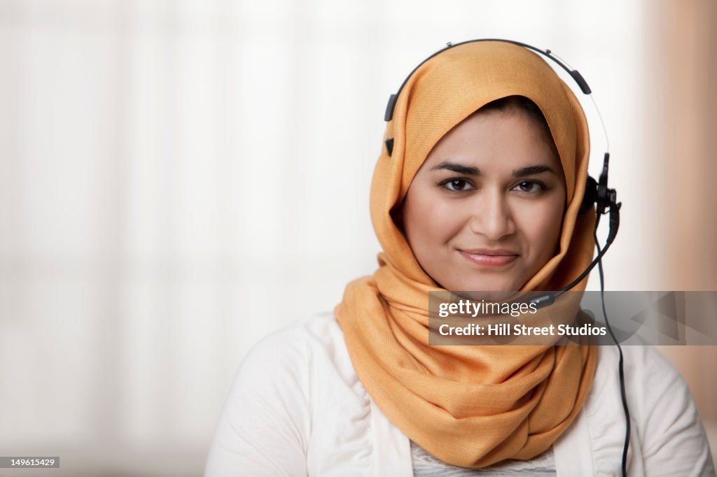 Mixed race businesswoman in hijab wearing headset